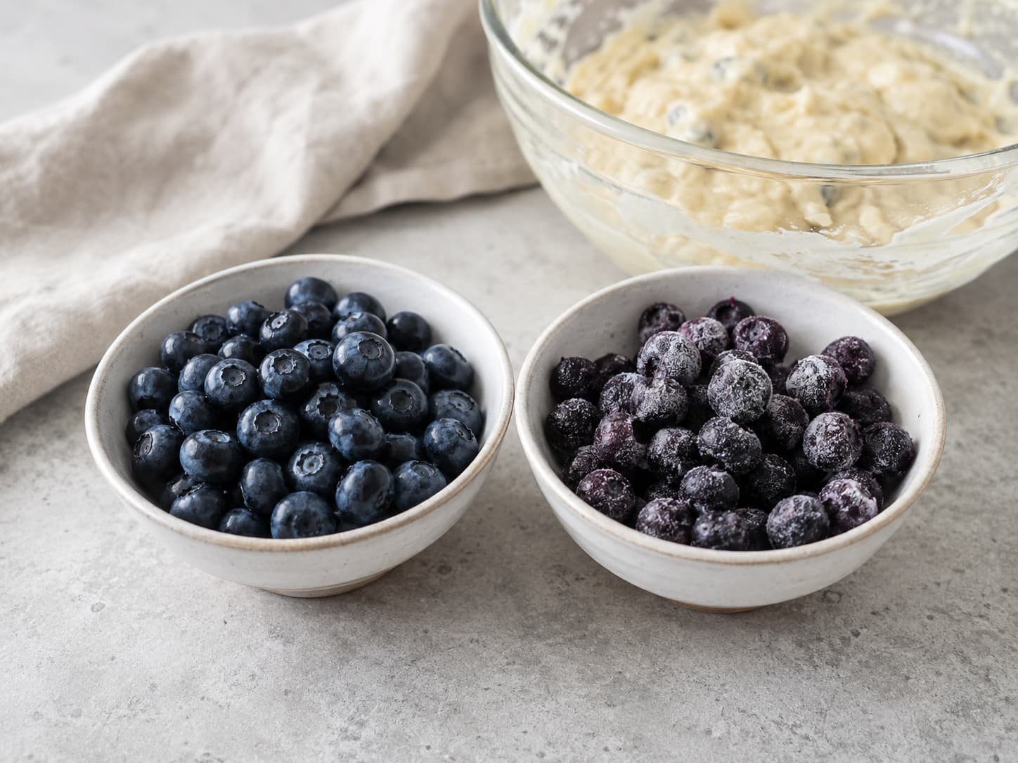 Fresh blueberries beside frozen blueberries for comparison in muffin baking 