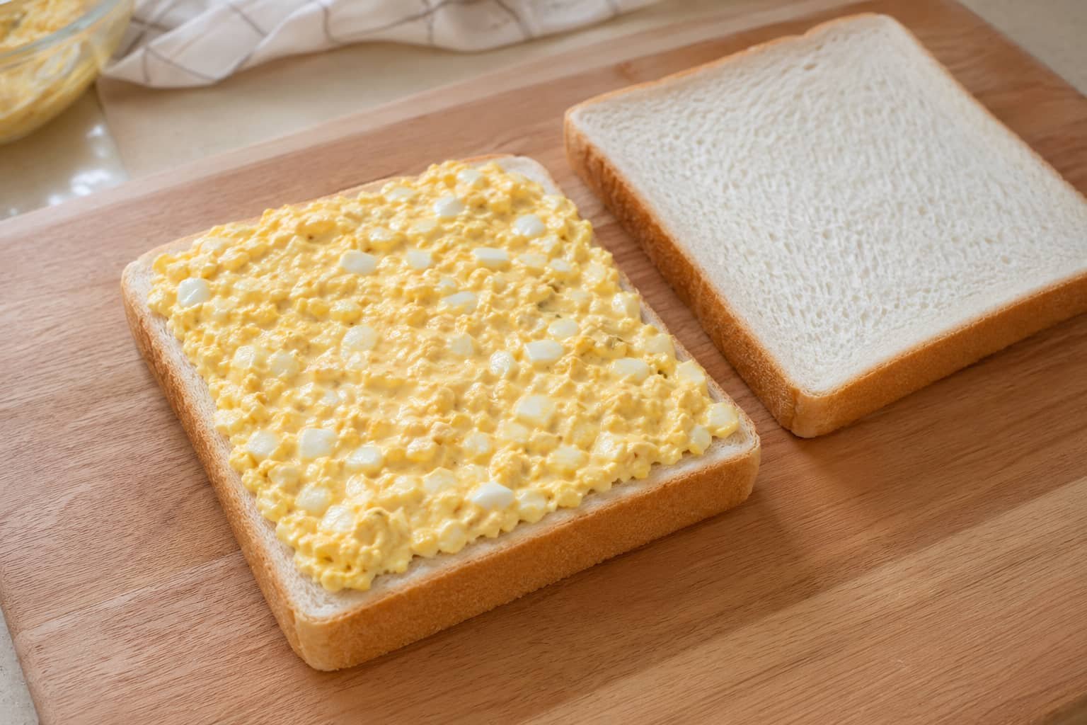 Japanese egg sandwich being assembled with creamy egg salad filling