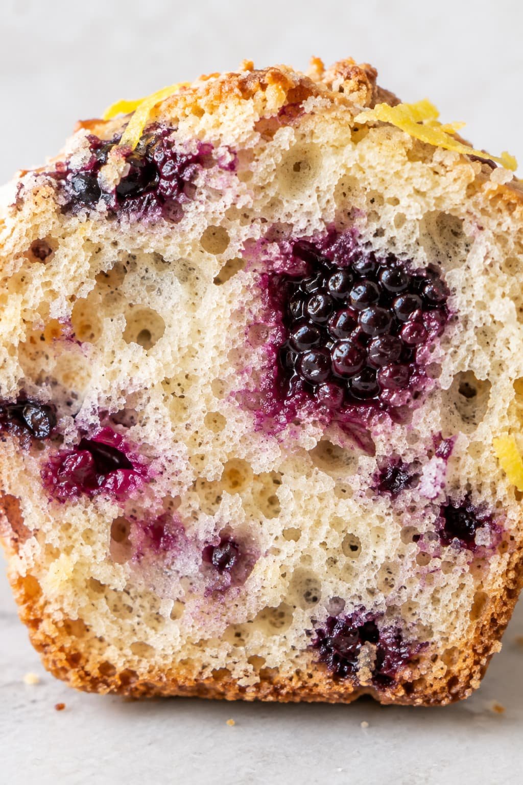 Macro cross-section of a baked muffin highlighting an airy, tender internal crumb structure and a suspended berry.