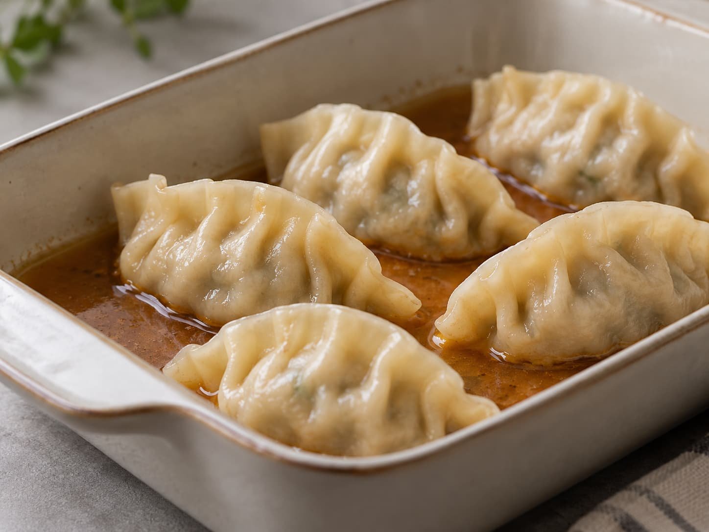 Dumplings partially surrounded by sauce, showing exposed and liquid-contact areas of the wrappers.