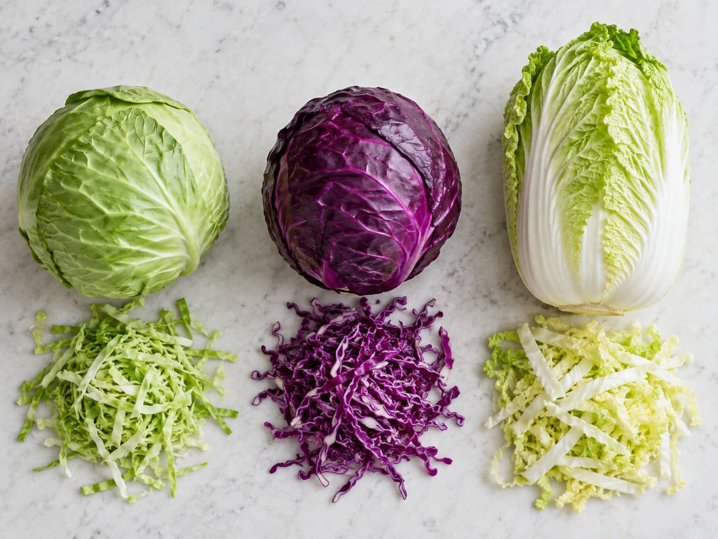 Green cabbage, red cabbage, and Napa cabbage shown with their different shredded textures