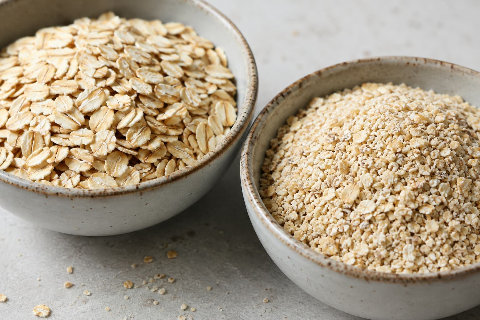 Old-fashioned rolled oats beside finer quick oats showing the difference in flake size