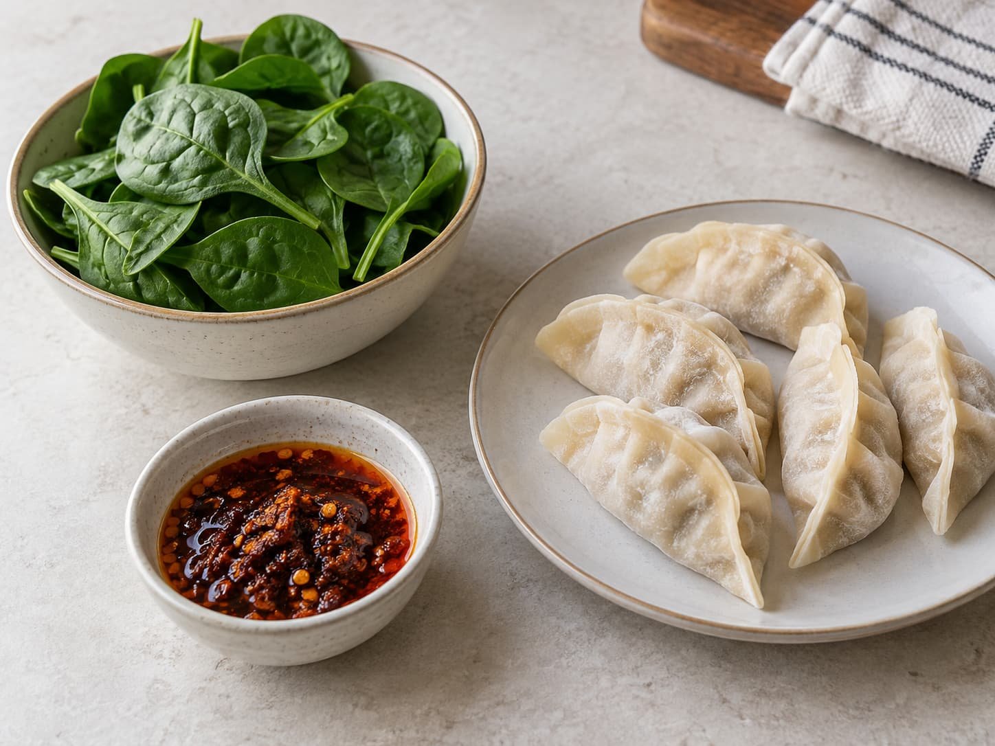 Spinach, chili crisp, and filled dumplings shown separately to illustrate their different roles in a dumpling bake.
